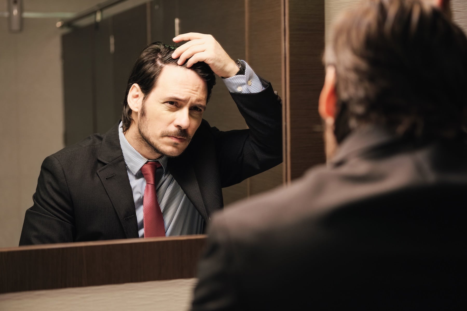 Мъж пред огледало притеснен за косата си