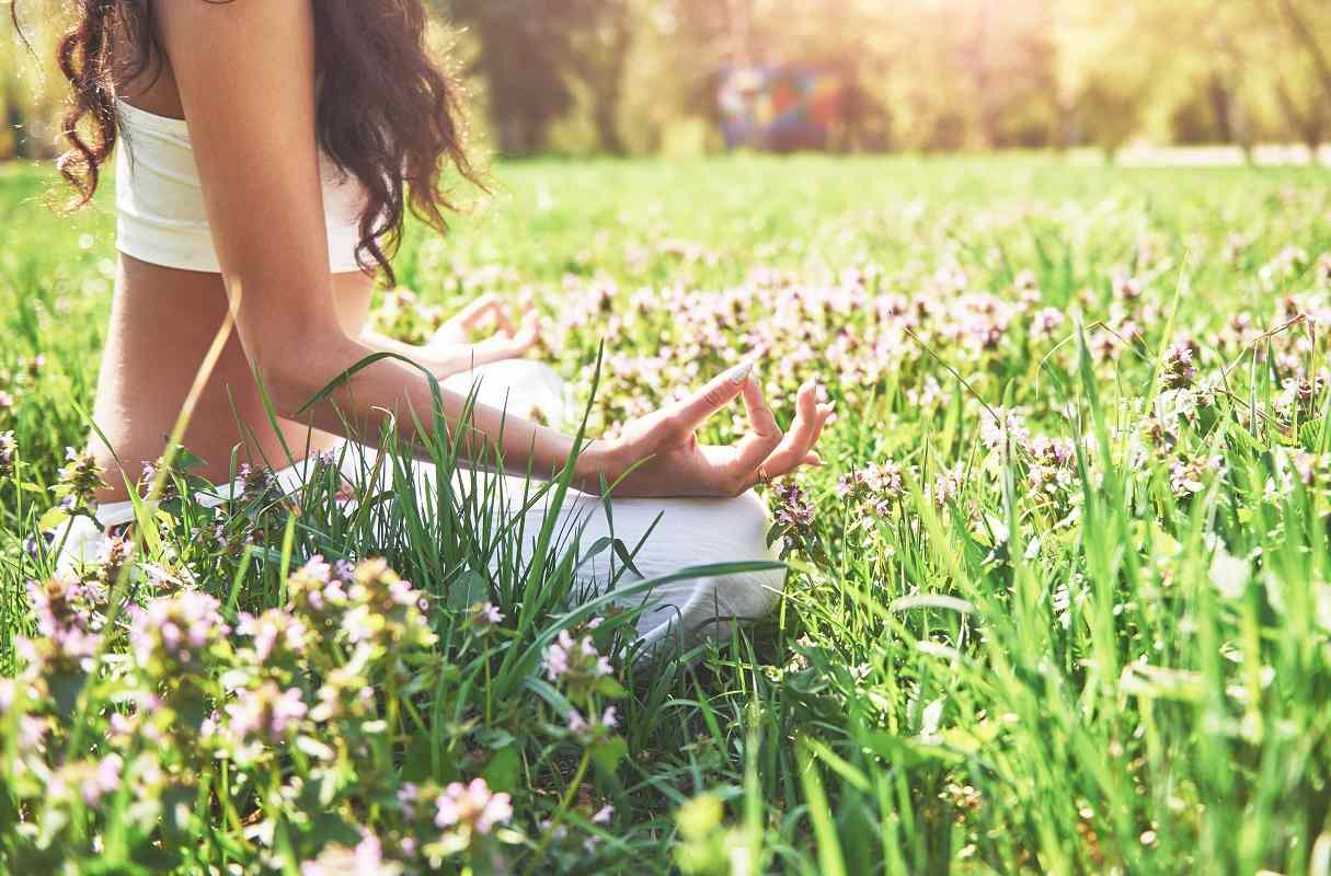 Жена прави йога на поляна с цветя