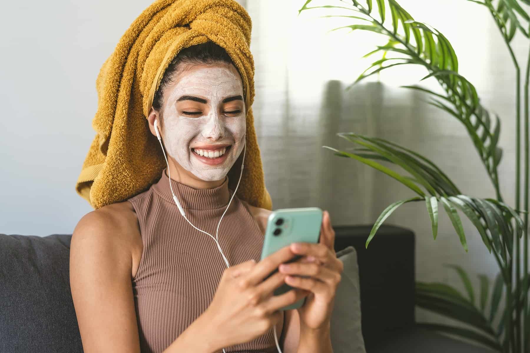 Жена с маска за лице използваща телефона си