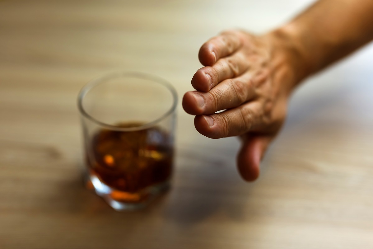 стъклена чаша с алкохол и ръка