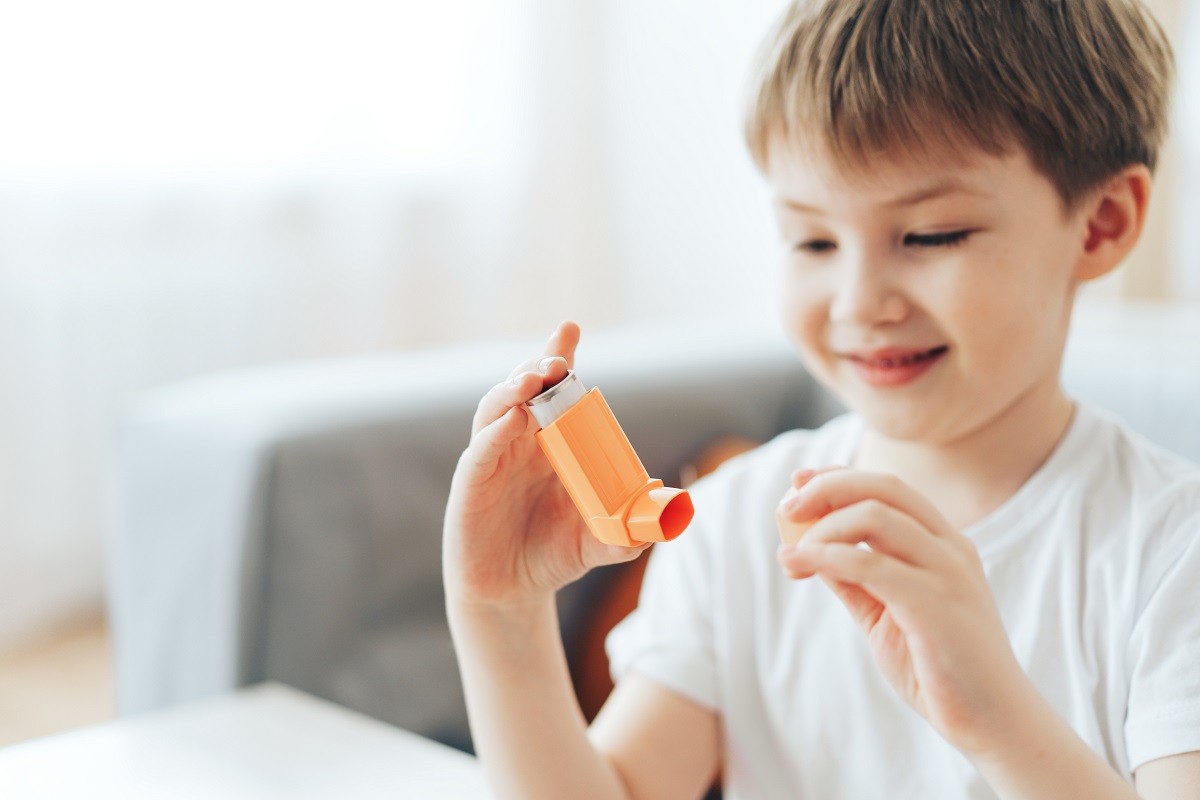 малко момче държи оранжев инхалатор