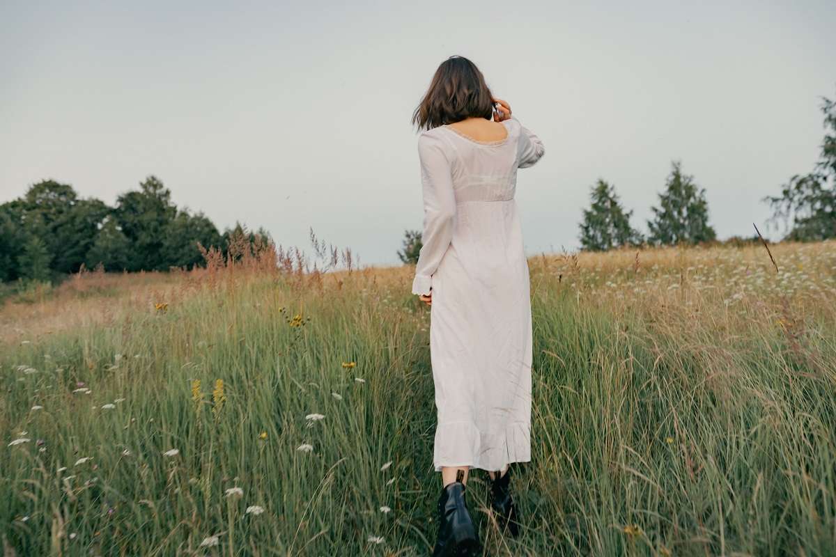 младо момиче със сива рокля се разхожда сред природата